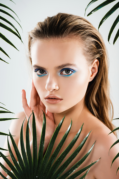 beautiful woman with makeup  near palm leaves on white