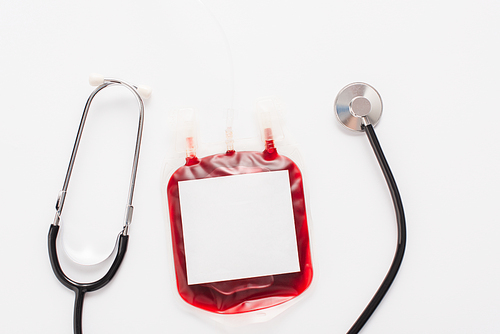 top view of blood donation package with blank label and stethoscope isolated on white