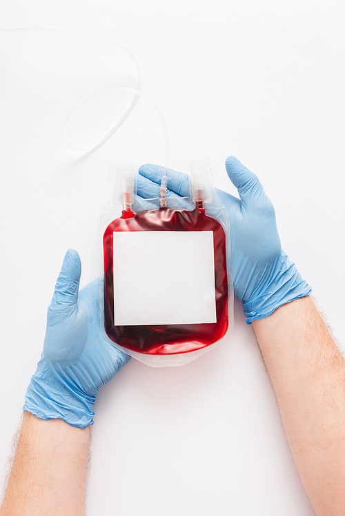 cropped view of doctor holding blood donation package with blank label on white background