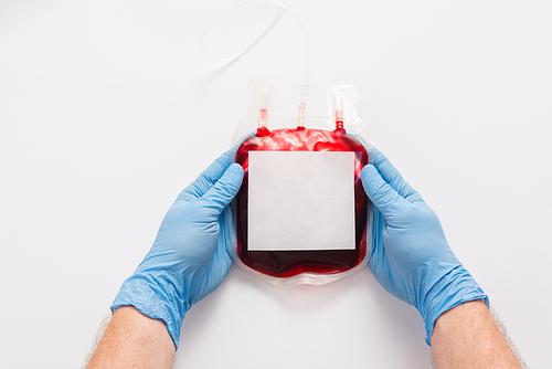 cropped view of doctor holding blood donation package with blank label on white background