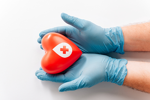 cropped view of male hands in latex gloves with red heart on white, blood donation concept