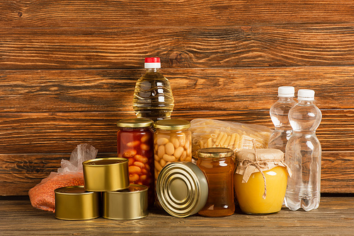 groats near water, oil, canned food and honey on wooden background, charity concept