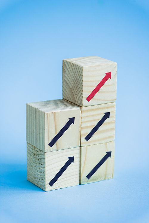 wooden blocks with black and red arrows on blue background, leadership concept