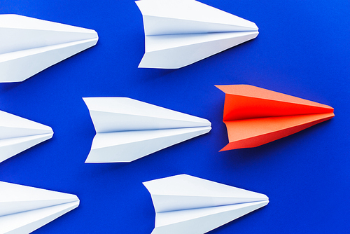 top view of white and red paper planes on blue background, leadership concept