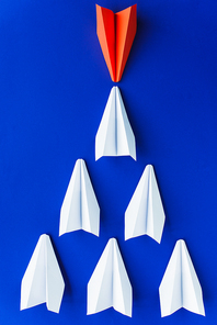 flat lay with white and red paper planes on blue background, leadership concept