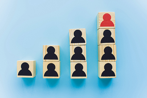 top view of wooden blocks with black and red human icons on blue background, leadership and career ladder concept