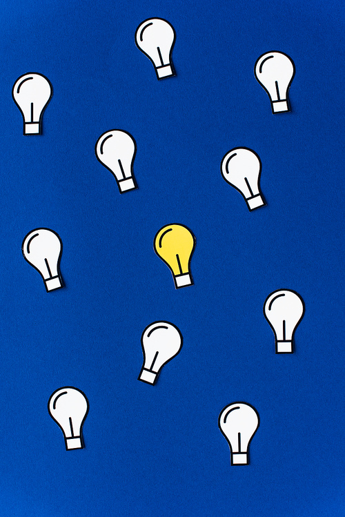 top view of paper light bulbs on blue background, business concept