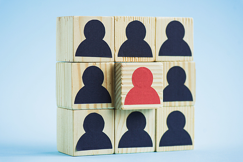 square of wooden blocks with black and red human icons on blue background, leadership concept