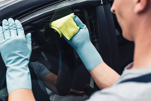 copped view of car cleaner wiping car door with rag