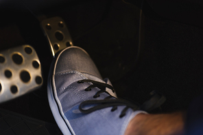 partial view of male leg in sneaker on brakes pedal