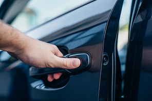 cropped view of man holding car door handle