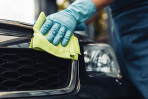 cropped view of car cleaner wiping radiator grille with rag