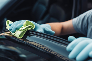 partial view of car cleaner wiping black car door with rag