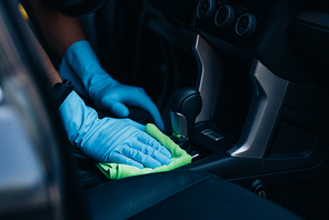 cropped view of car dealer wiping gear shifter with rag