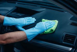 cropped view of car cleaner wiping dashboard with rag