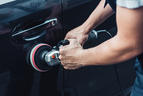 partial view of car cleaner polishing black car door with buffer machine