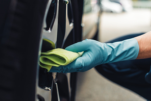 partial view of car cleaner wiping car wheel with rag