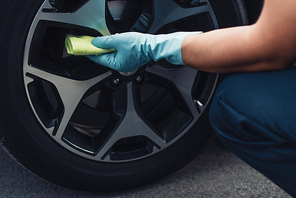 cropped view of car cleaner wiping car wheel with rag