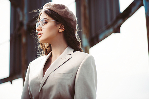 beautiful woman posing in beige suit and trendy beret on roof