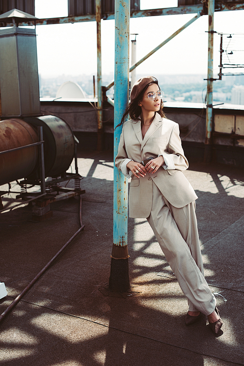 attractive stylish girl posing in beige suit and beret on roof