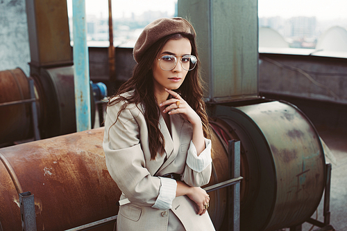 elegant stylish model posing in beige suit and beret on urban roof