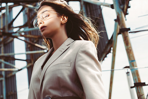 attractive fashionable girl posing with closed eyes in beige suit and beret on urban roof