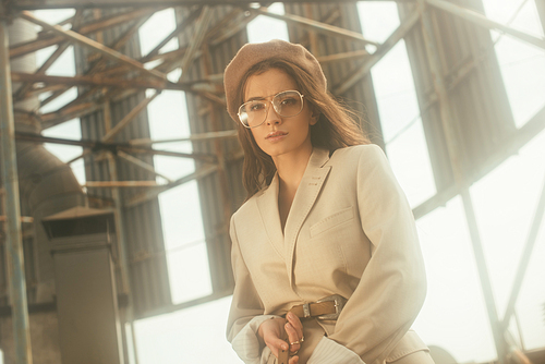 fashionable girl posing in beige suit and beret on urban roof