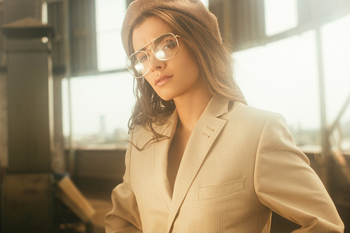 beautiful stylish girl posing in beige suit and beret on urban roof