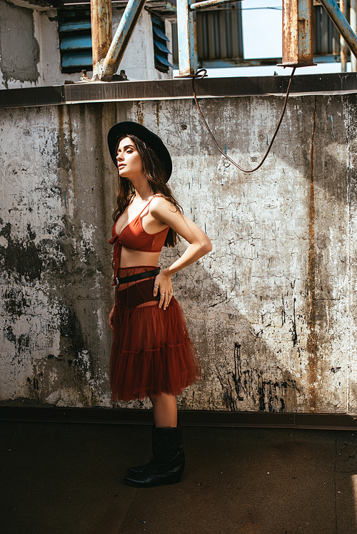 attractive stylish girl posing in red skirt, bra and hat on roof