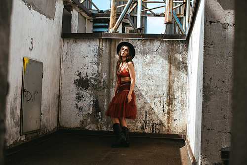 beautiful fashionable woman posing in red skirt, bra and hat on roof