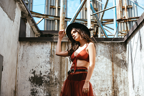 beautiful woman posing in red skirt, bra and hat on roof