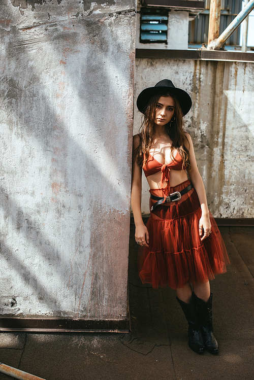 stylish beautiful woman posing in red skirt, bra and hat on roof