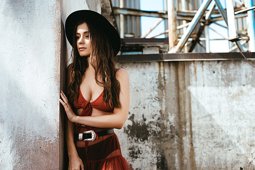 attractive trendy woman posing in red skirt, bra and hat on roof