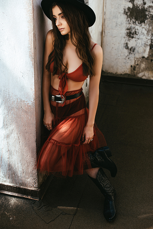 beautiful fashionable woman posing in red skirt, bra and hat on roof