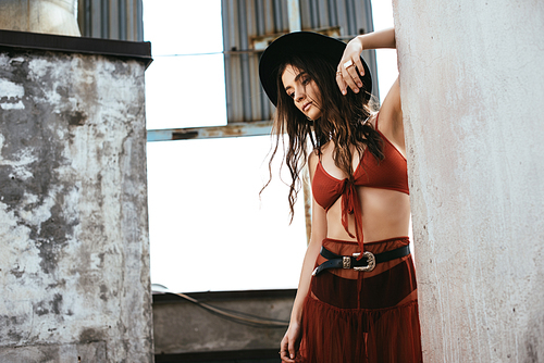 stylish woman posing in red skirt, bra and hat on roof