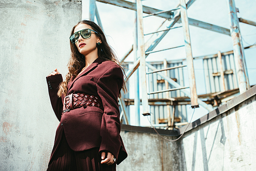 stylish model posing in trendy burgundy suit and sunglasses on urban roof