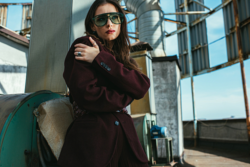 elegant beautiful woman posing in trendy burgundy suit and sunglasses on urban roof