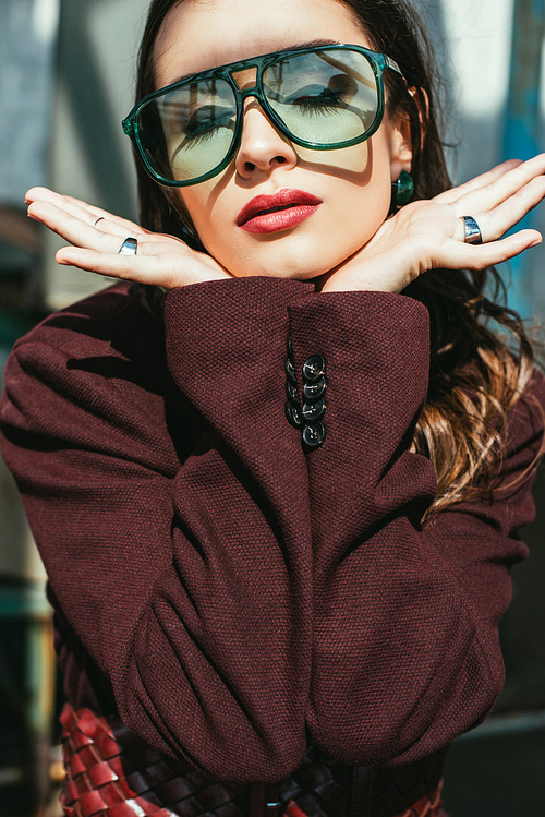 elegant woman posing in trendy burgundy suit and sunglasses on urban roof