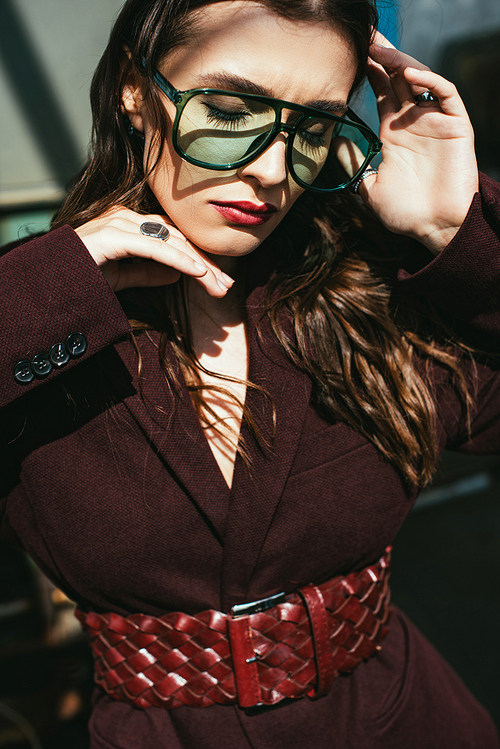 elegant girl posing in trendy burgundy suit and sunglasses on urban roof