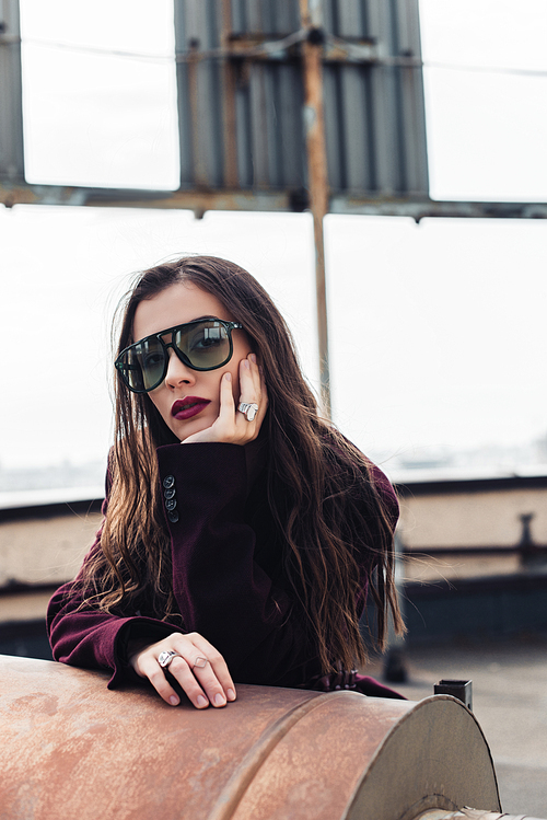 beautiful elegant girl posing in trendy burgundy suit and sunglasses on urban roof