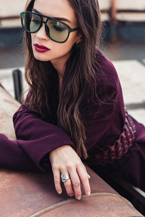 attractive elegant girl posing in trendy burgundy suit and sunglasses on urban roof