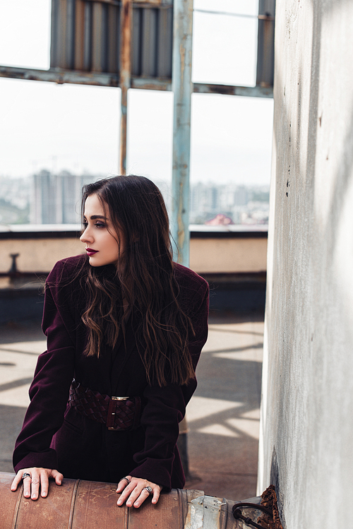 beautiful elegant girl posing in trendy burgundy suit on urban roof