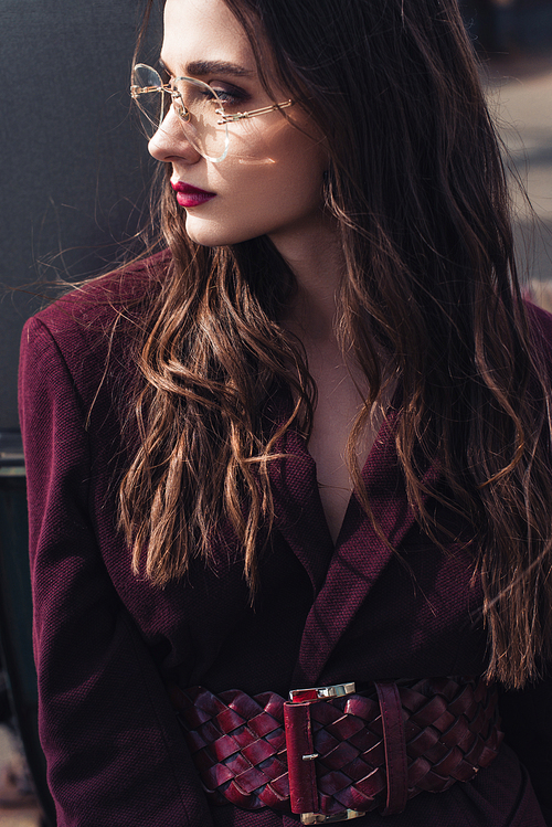 fashionable girl posing in trendy burgundy suit and sunglasses on urban roof