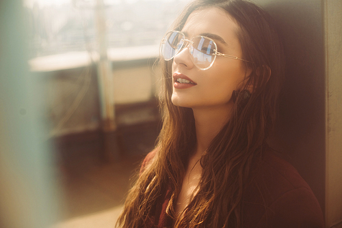 stylish young woman posing in trendy burgundy suit and sunglasses on urban roof