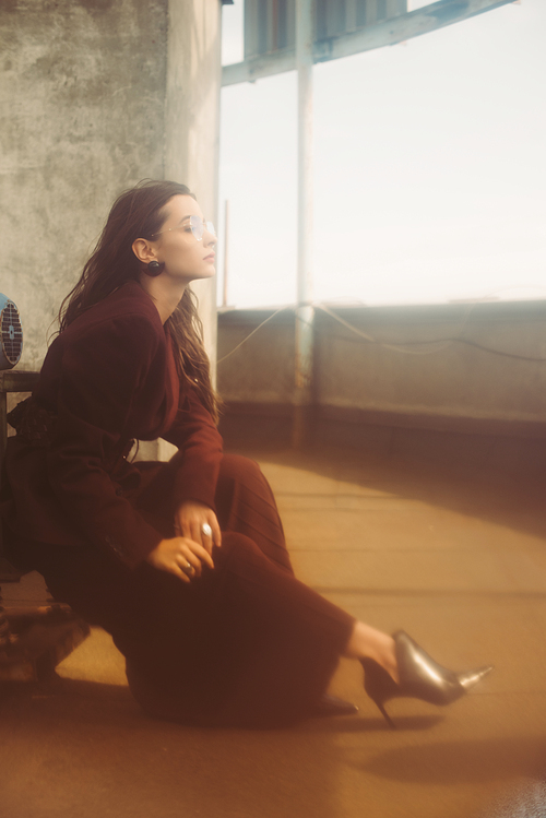 elegant fashionable girl posing in trendy burgundy suit and sunglasses on urban roof