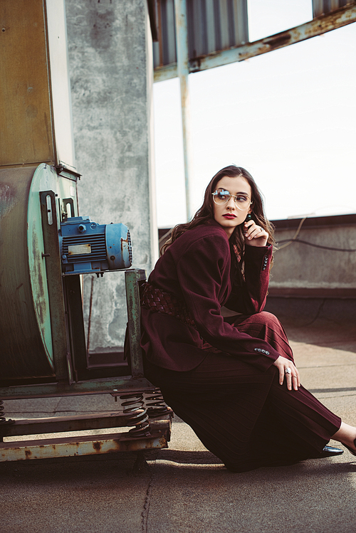 beautiful elegant girl posing in trendy burgundy suit and sunglasses on urban roof