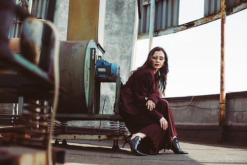 stylish girl posing in trendy burgundy suit and sunglasses on urban roof