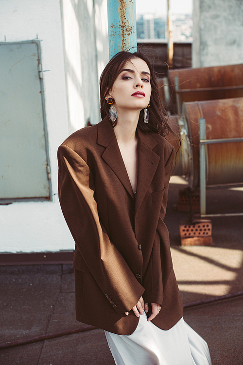 beautiful stylish girl posing in silk dress and brown jacket on roof
