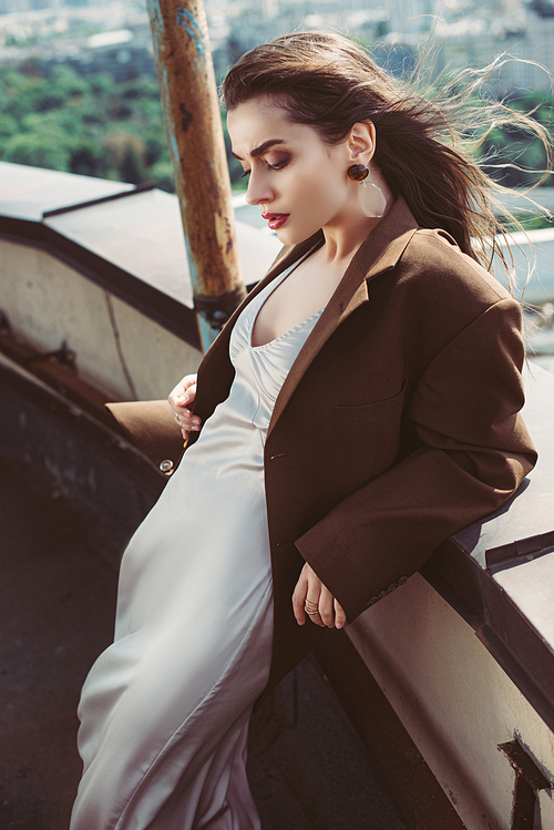 stylish elegant girl posing in silk dress and brown jacket on roof