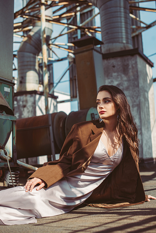 stylish elegant woman posing in silk dress and brown jacket on roof